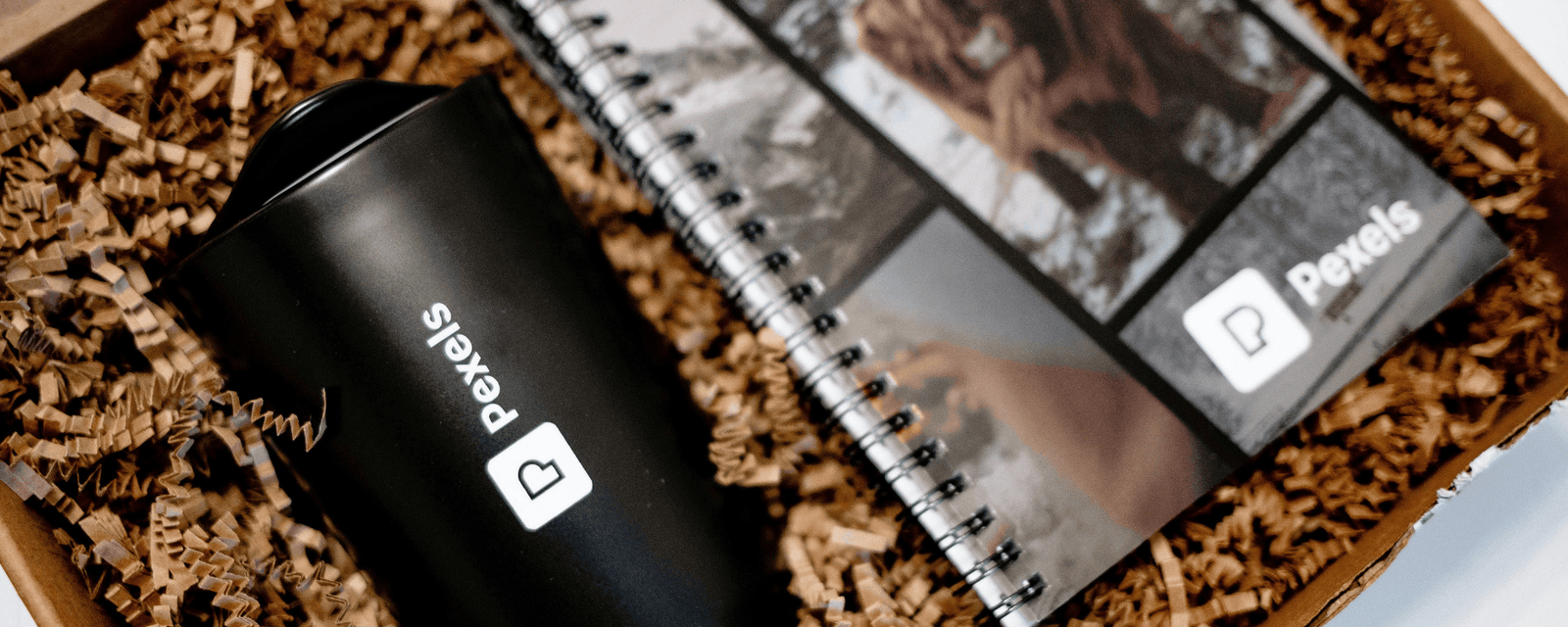 Branded drinkware, tote bags, pens, and notebooks laid out together